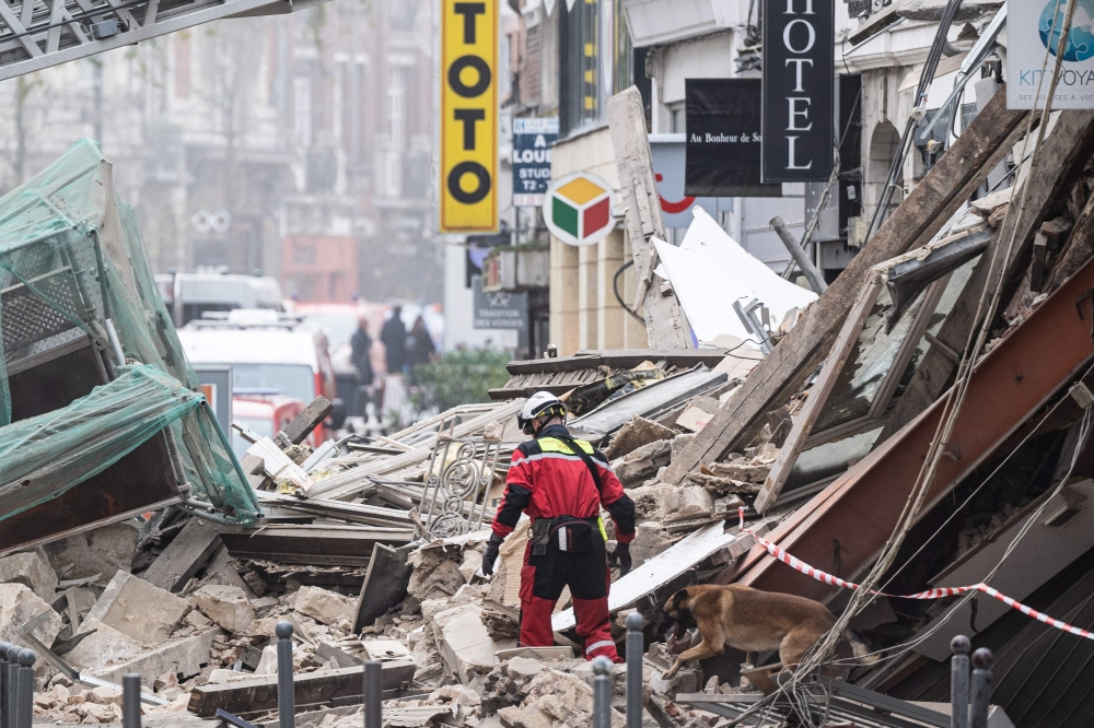 Firefighters inspect a collapsed building as they search for victims in the city of Lille, northern France, on November 12, 2022. (Photo by Sameer Al-DOUMY / AFP)