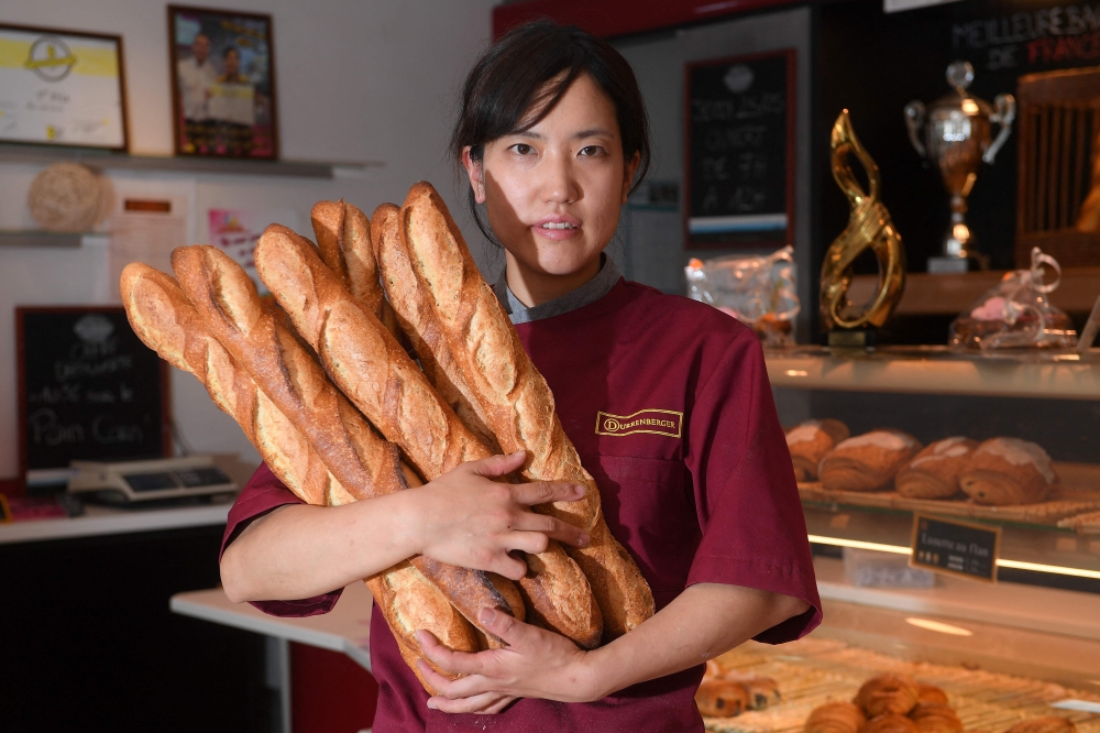 In this file photo taken on May 25, 2017, Japanese baker Mei Narusawa poses while holding baguettes in the Durrenberger bakery in Mertzwiller, eastern France. (Photo by PATRICK HERTZOG / AFP)