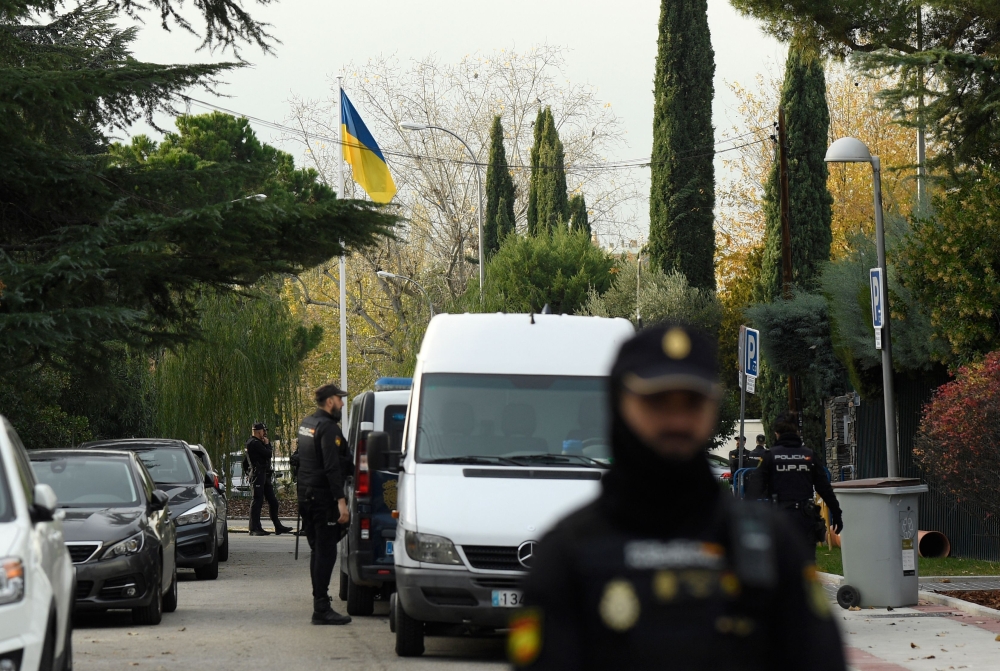 Spanish policemen stand next to a Ukrainian flag while securing the area after a letter bomb explosion at the Ukraine's embassy in Madrid on November 30, 2022. (AFP/Oscar del Pozo)