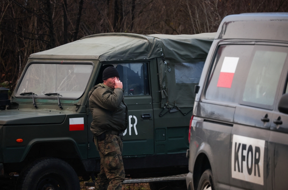 A member of the Polish Armed Forces, part of NATO peacekeepers mission in Kosovo, walks near the barricade in the northern part of the ethnically-divided town of Mitrovica, Kosovo, on December 11, 2022. REUTERS/Florion Goga