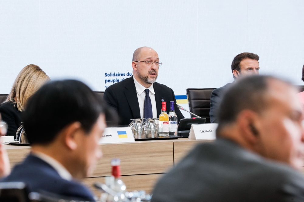 Ukrainian Prime Minister Denys Shmyhal (centre) and French President Emmanuel Macron (right) at the 'Solidarity with Ukrainian people' conference, at the French Foreign Affairs ministry, in Paris, on December 13, 2022. (Photo by Teresa SUAREZ / AFP)