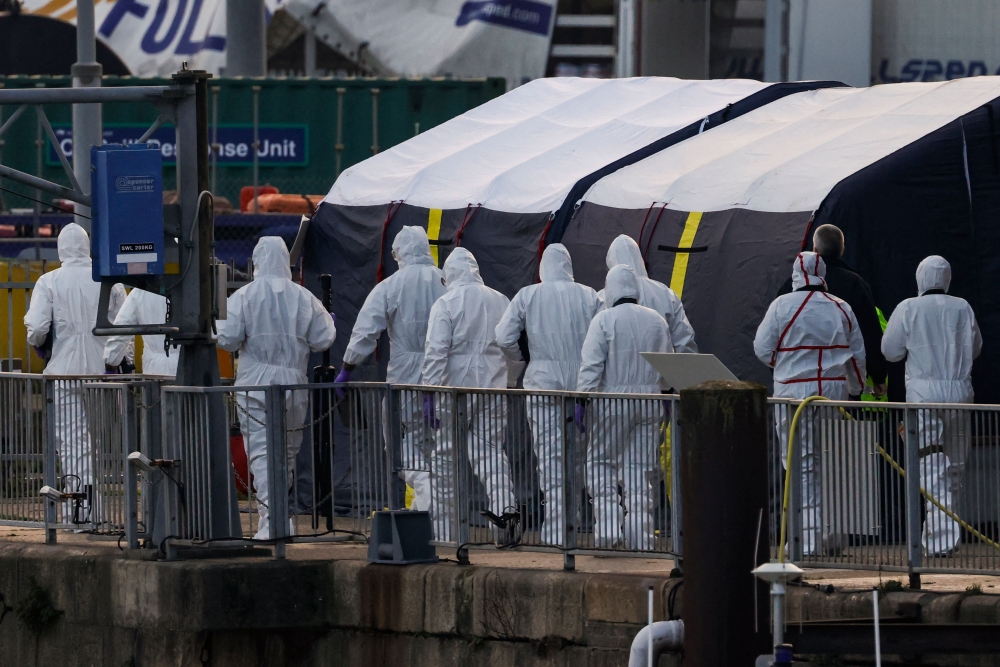 Forensics police officers arrive at the marina in Dover, southeast England, on December 14, 2022 to inspect the bodies of migrants believed to be kept inside a tent outside the UK Royal National Lifeboat Institution (RNLI) office after they died overnight while attempting to cross the English Channel. (Photo by CARLOS JASSO / AFP)