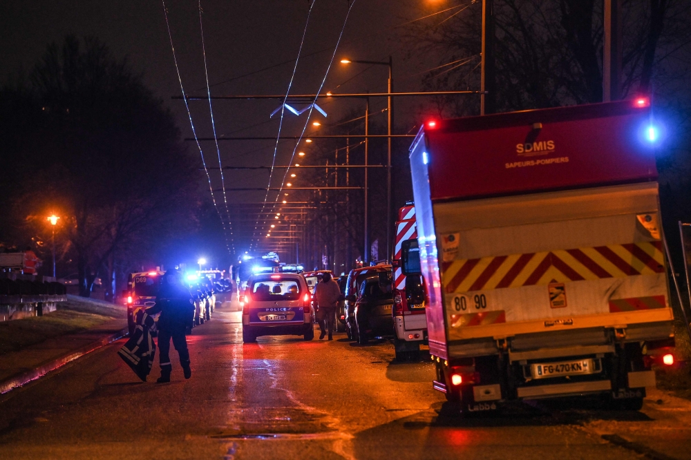 Policemen guard a security perimeter as firefighters and rescuers work in a building of the Mas-Du-Taureau quarter where a fire caused many victims, including children, on December 16, 2022 in Vaulx-en-Velin. Photo by OLIVIER CHASSIGNOLE / AFP