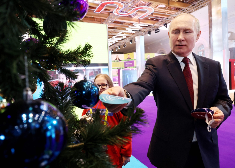 Russian President Vladimir Putin takes a child's request pinned in written form to a fir tree during an event held as part of the 'Fir Tree of Wishes' charity campaign at the Manezh Central Exhibition Hall in Moscow on December 22, 2022. (Photo by Valeriy Sharifulin / POOL / AFP)