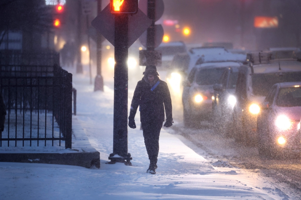 A pedestrian navigates a snow-covered sidewalk as temperatures hang in the single-digits on December 22, 2022 in Chicago, Illinois. Photo by SCOTT OLSON / GETTY IMAGES NORTH AMERICA / Getty Images via AFP