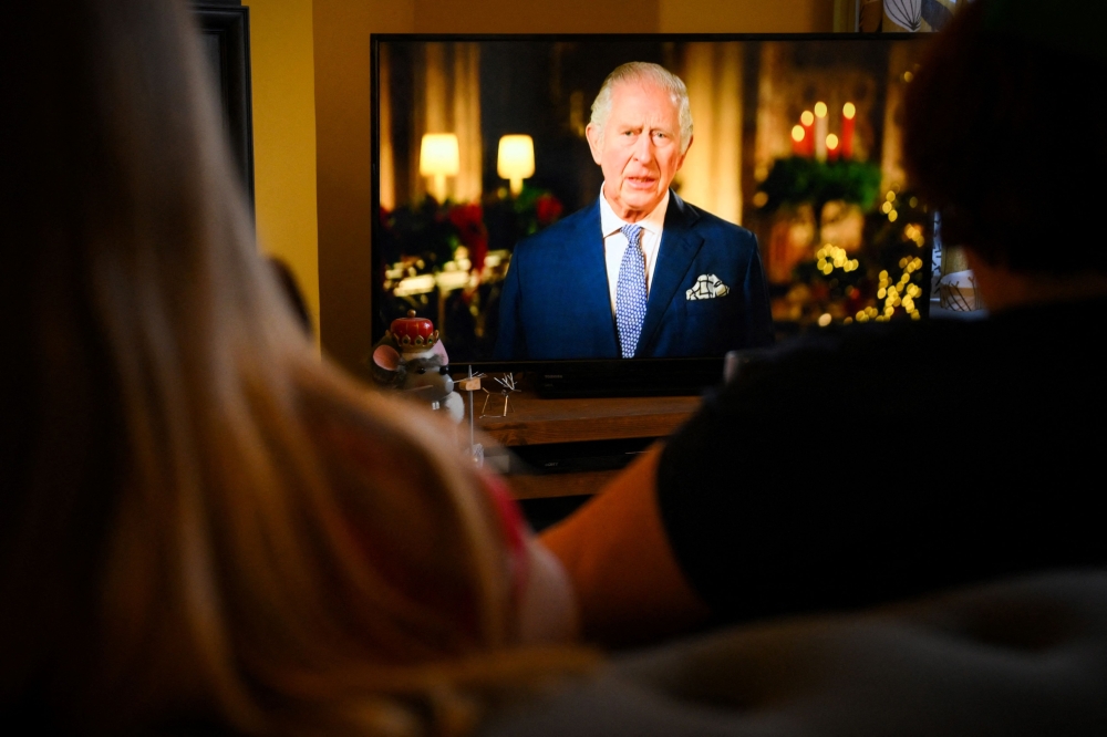 A family sits in a living room in Liverpool, as they watch Britain's King Charles III delivering his first annual Christmas Day message, on television, on December 25, 2022. (Photo by Paul ELLIS / AFP)