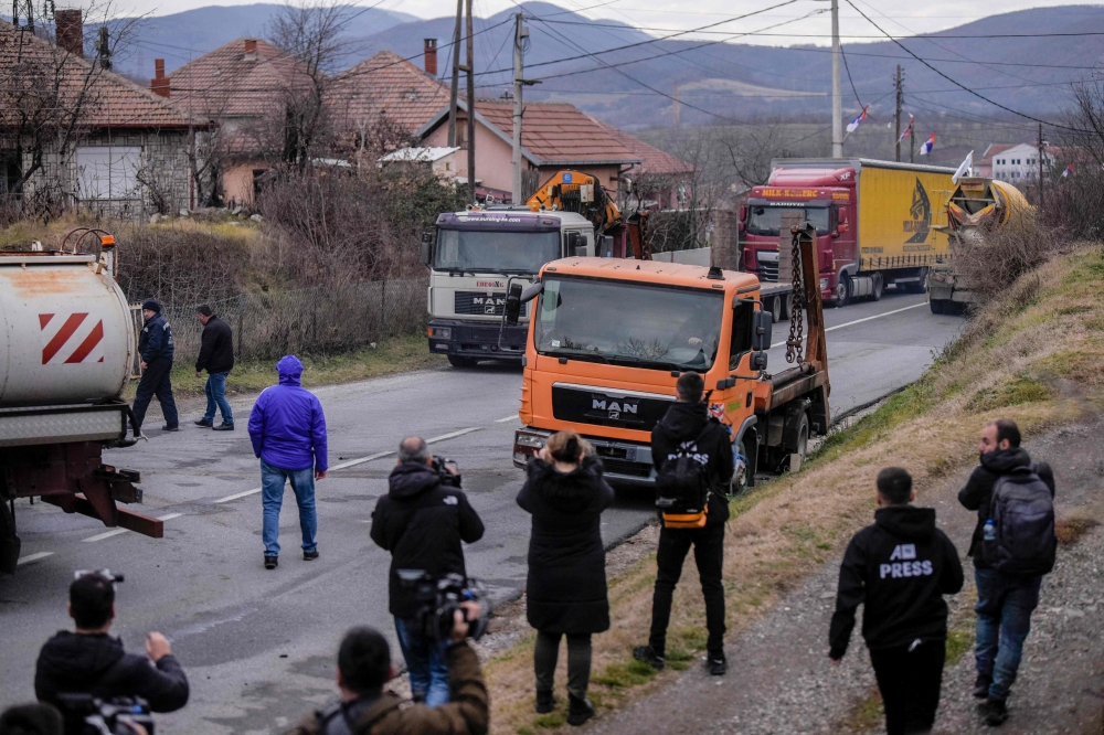 Journalists film as Kosovo Serbs remove trucks from a road barricade set up by ethnic Serbs in the village of Rudare near the town of Zvecan on December 29, 2022.  (Photo by Armend NIMANI / AFP)