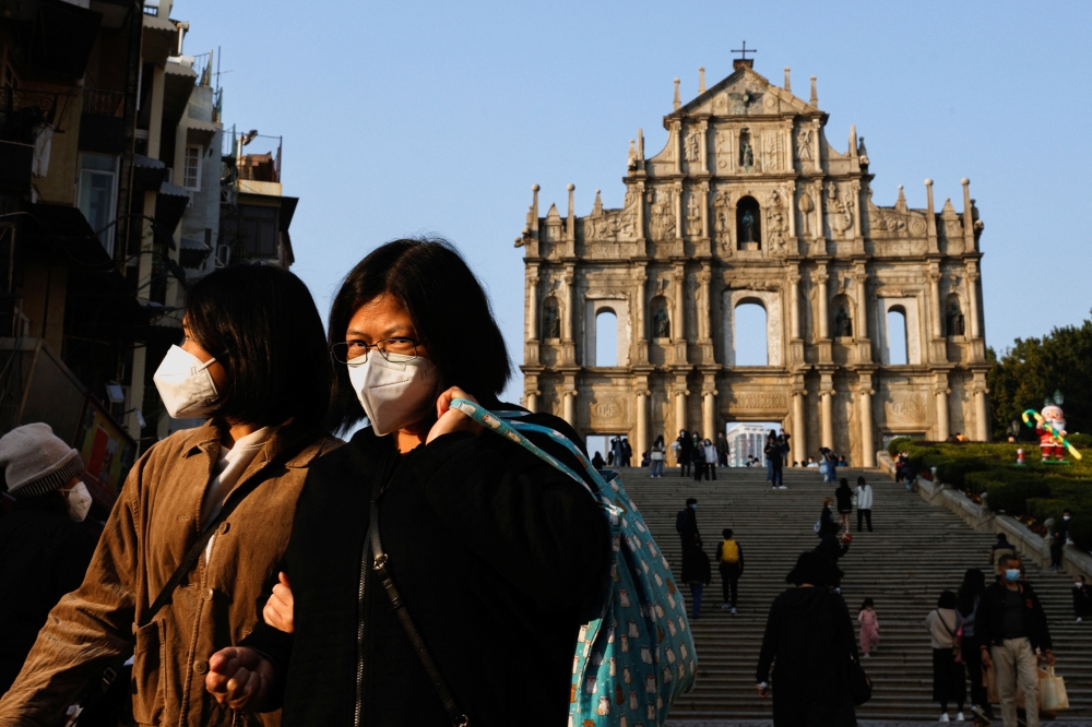 People wearing face masks walk in front of the ruins of Saint Paul's during the coronavirus disease (COVID-19) pandemic in Macau, China, December 29, 2022. REUTERS/Tyrone Siu