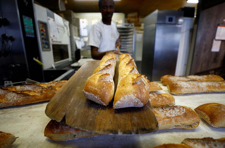 A baker shows freshly-baked baguettes at 