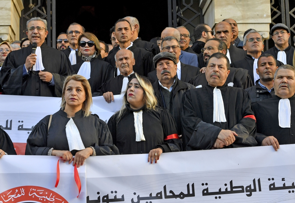 Tunisian lawyers wear a red armband during a lawyers sit in protest against the new finance law, in front of the Tunis court, on January 5, 2023. (Photo by FETHI BELAID / AFP)