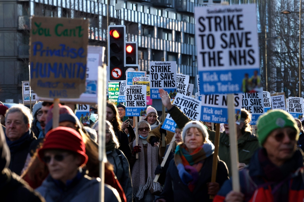 People hold placards as they take part in a protest march organised by Doctors Association UK, NHS Workers Say No! and NHS Staff Voices, from University College London to Downing Street, in London on January 18, 2023, in support of the ongoing pay disputes.  (Photo by CARLOS JASSO / AFP)