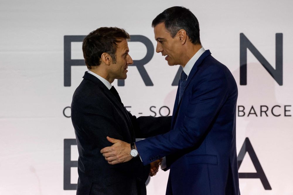 Spain's Prime Minister Pedro Sanchez (right) and France's President Emmanuel Macron shake hands at the end of a press conference after signing a treaty during a Franco-Spanish summit in Barcelona on January 19, 2023.  (Photo by Ludovic MARIN / AFP)