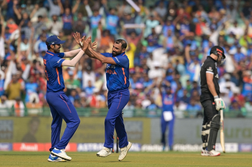India's Mohammed Shami (C) celebrates after taking the wicket of New Zealand's Daryl Mitchell (R) in Raipur on January 21, 2023. (Photo by Money Sharma / AFP)