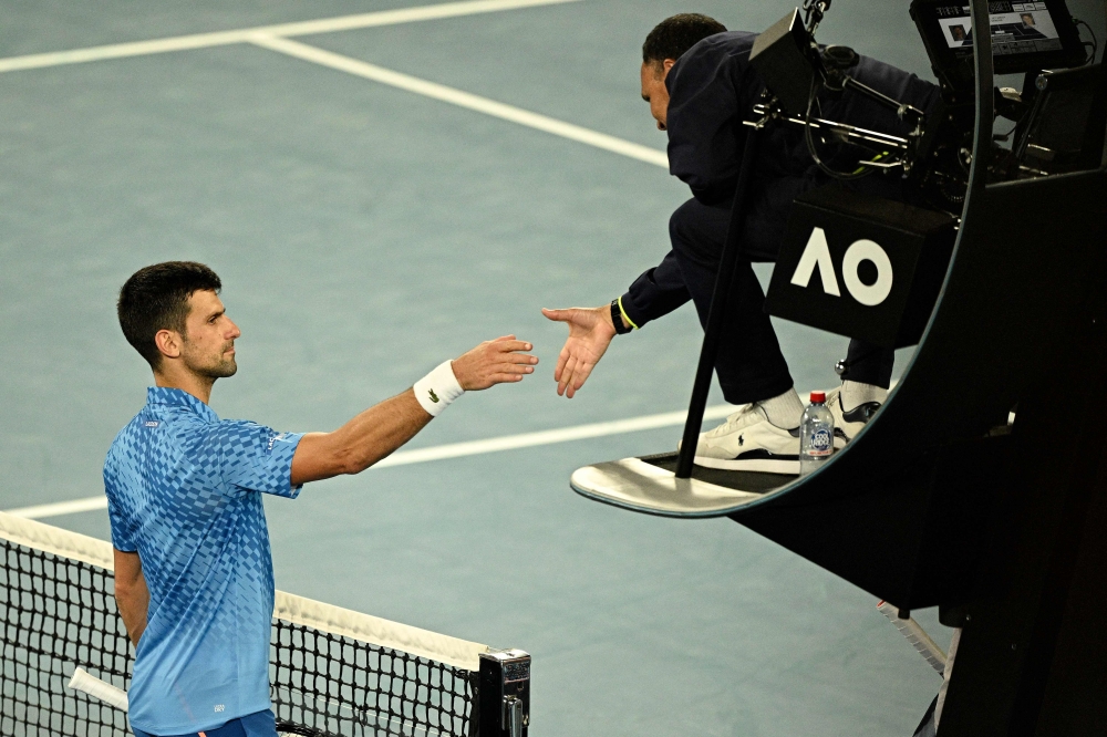 Serbia's Novak Djokovic shakes hands with the umpire after the men's singles match against Australia's Alex De Minaur on day eight of the Australian Open tennis tournament in Melbourne on January 23, 2023. (Photo by ANTHONY WALLACE / AFP)