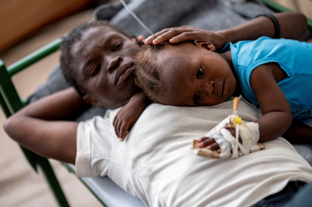 Karina Joseph, 19, comforts her 2-year-old child Holanda Sineus as she receives treatment for cholera in a tent at a Doctors Without Borders hospital in Cite Soleil, a densely populated commune of Port-au-Prince, Haiti October 15, 2022. File Photo: REUTERS/Ricardo Arduengo/File Photo