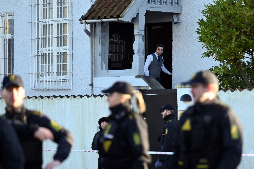 A man looks out of the Turkish embassy as police secure the area in front of the Turkish embassy in Copenhagen, on January 27, 2023. (Photo by Sergei GAPON / AFP)