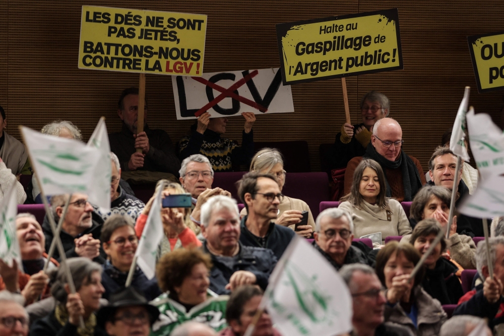 Protesters hold placards reading (LtoR) 