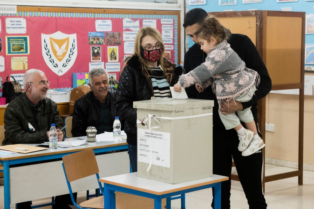 A Cypriot man carries his daughter as he votes in presidential elections with his daughter at a Limassol polling centre on February 5, 2023.  (Photo by Iakovos Hatzistavrou / AFP)