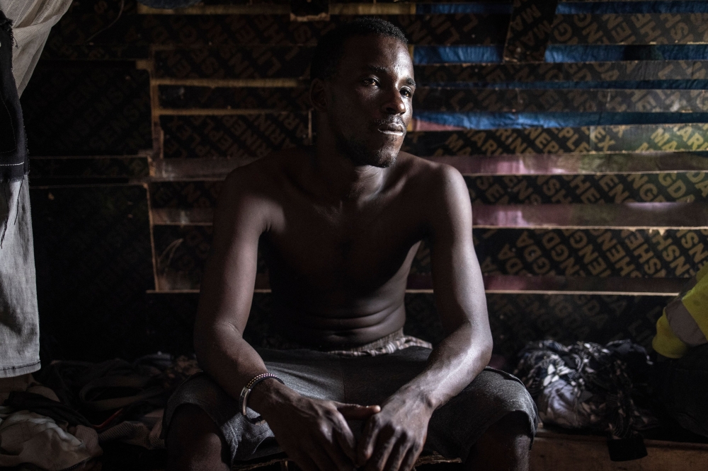 A construction worker from Guinea Conakry looks on during a lunch break in Diamniadio on November 15, 2022. - Young men from Sierra Leone, Guinea and even distant Nigeria have flocked to Diamniadio, lured by the vision of a decent job and pay in a stable currency. They are among thousands of labourers toiling on construction sites across the budding city. (Photo by JOHN WESSELS / AFP)