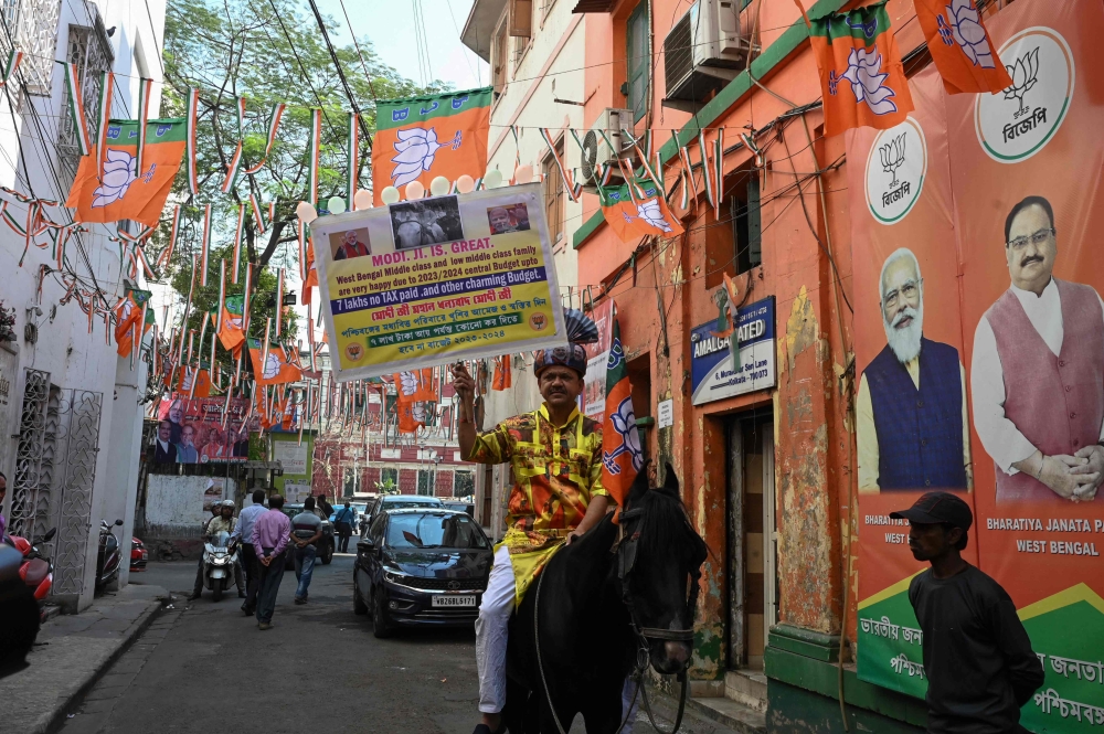 A Bharatiya Janata Party (BJP) activist holds a placard in support of India's Prime Minister Narendra Modi and the union budget while riding a horse in Kolkata on February 7, 2023. (Photo by DIBYANGSHU SARKAR / AFP)