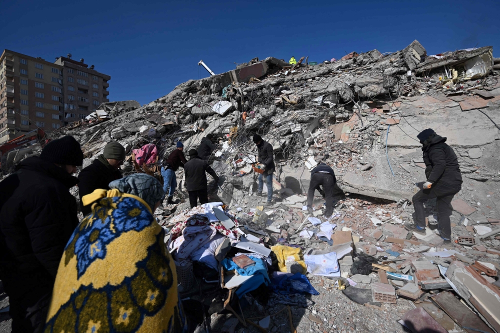 People search for missing relatives in the rubble of a collapsed building in the southeastern Turkish city of Kahramanmaras, on February 8, 2023, two days after a strong earthquake struck the region. (Photo by OZAN KOSE / AFP)