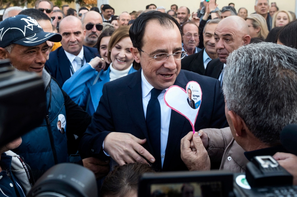 Former Cypriot foreign minister and presidential candidate Nikos Christodoulides is flanked by supporters as he arrives to cast his vote at the Geroskypou polling centre in the western Paphos district, on February 12, 2023. (Photo by Iakovos Hatzistavrou / AFP)