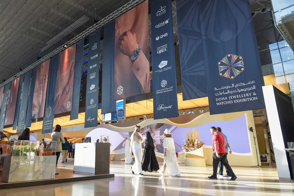 Individuals walking near Doha Jewellery and Watches Exhibition at the DECC. 