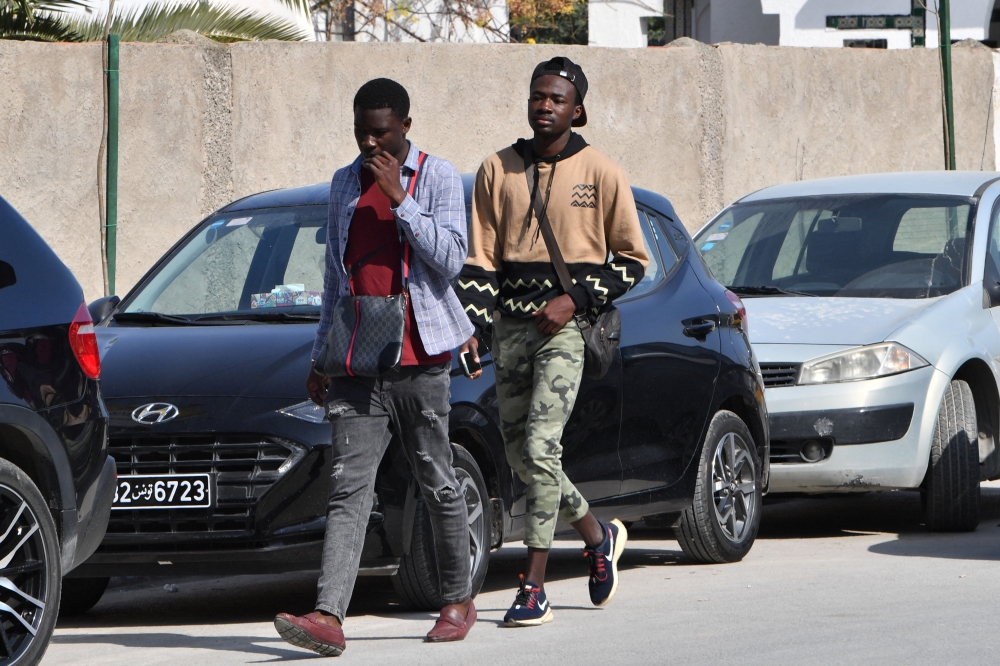 Sub-Saharan African men walk in the popular Ariana souk near Tunis on February 22, 2023. - A prominent rights group accused Tunisian President Kais Saied of 