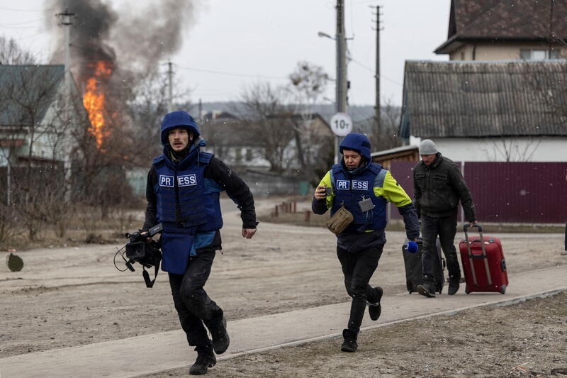Journalists run for cover after heavy shelling in Irpin, near Kyiv. REUTERS/Carlos Barria