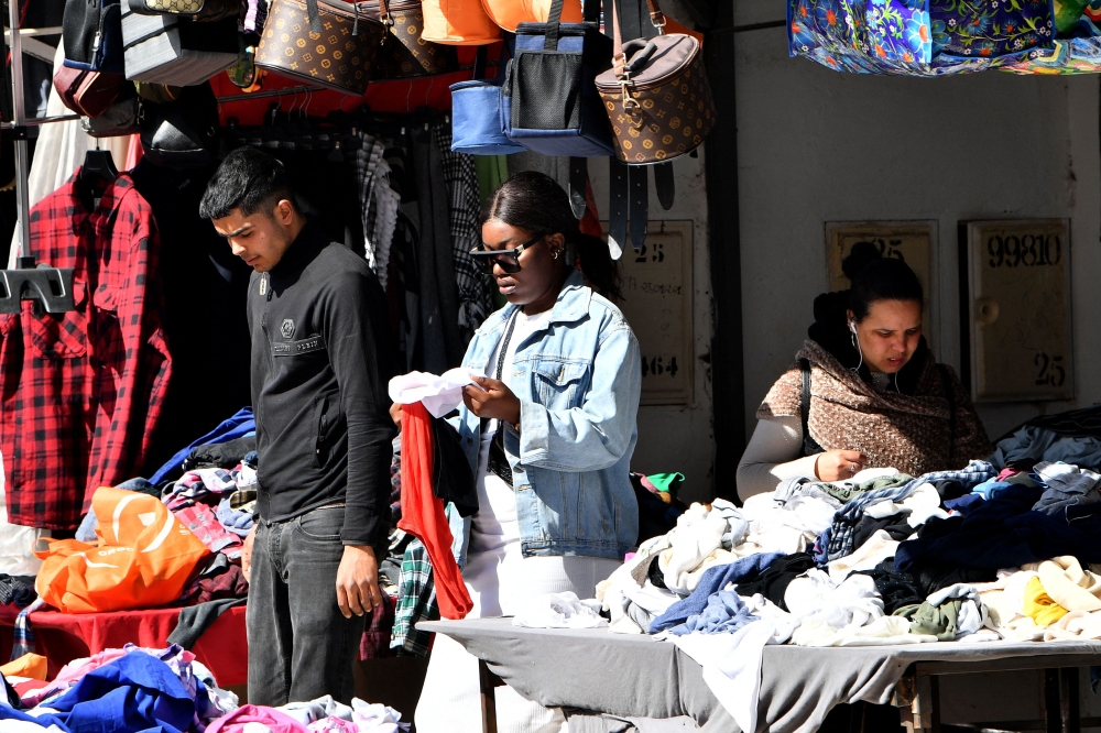 A sub-Saharan African woman (centre) looks for clothes in a thrift store in the popular Ariana souk near Tunis on February 22, 2023.  (Photo by FETHI BELAID / AFP)