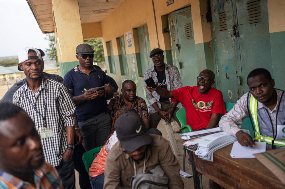 People watch as ballot papers are counted at a polling station in Abuja on February 25, 2023, during Nigeria's presidential and general election. (Photo by Michele Spatari / AFP)
 