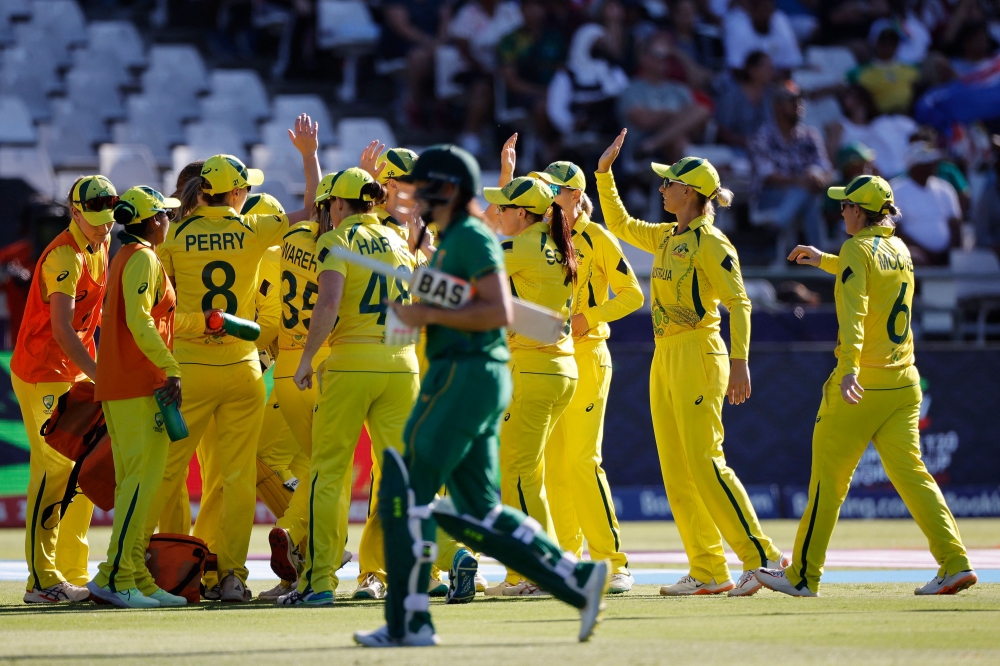 Australia's players celebrate as South Africa's Tazmin Brits (front) walks back to the pavilion after her dismissal during the final T20 women's World Cup cricket match between South Africa and Australia at Newlands Stadium in Cape Town on February 26, 2023. (Photo by Marco Longari / AFP)