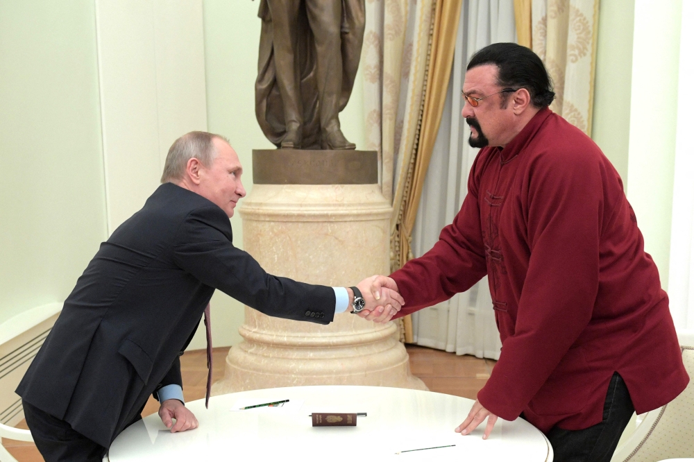 In this file photo taken on November 25, 2016 Russian President Vladimir Putin shakes hands with US action hero actor Steven Seagal after presenting a Russian passport to him during a meeting at the Kremlin in Moscow.  (Photo by Alexey DRUZHININ / SPUTNIK / AFP)