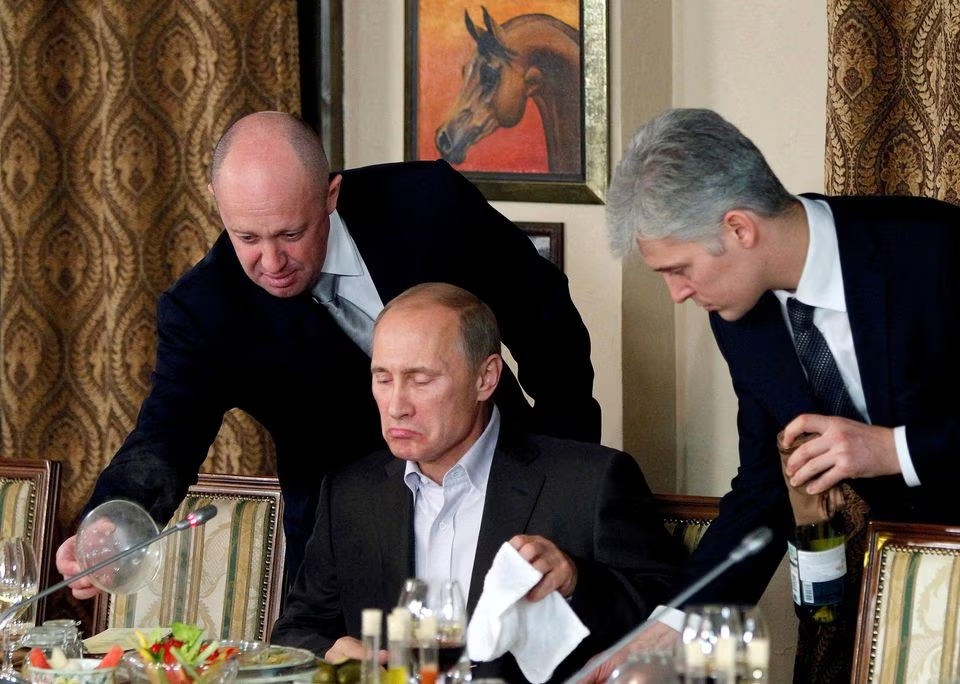 Evgeny Prigozhin (L) assists Russian Prime Minister Vladimir Putin during a dinner with foreign scholars and journalists at the restaurant Cheval Blanc on the premises of an equestrian complex outside Moscow November 11, 2011. REUTERS/Misha Japaridze/File Photo