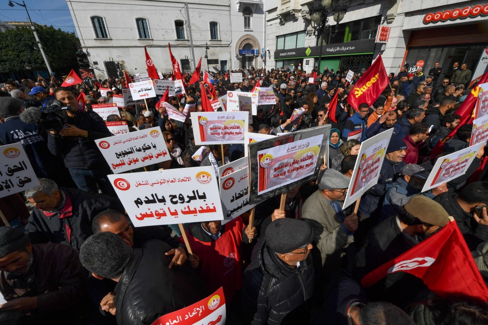 Demonstrators lift placards during an anti-government demostration called for by the powerful trades union federation UGTT in Tunis, on March 4, 2023. (Photo by FETHI BELAID / AFP)
