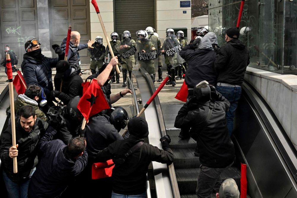 Protesters run from police into a metro station during a massive demonstration in Athens on March 5, 2023, following the deadly train accident late on February 28. (Photo by Louisa Gouliamaki / AFP)