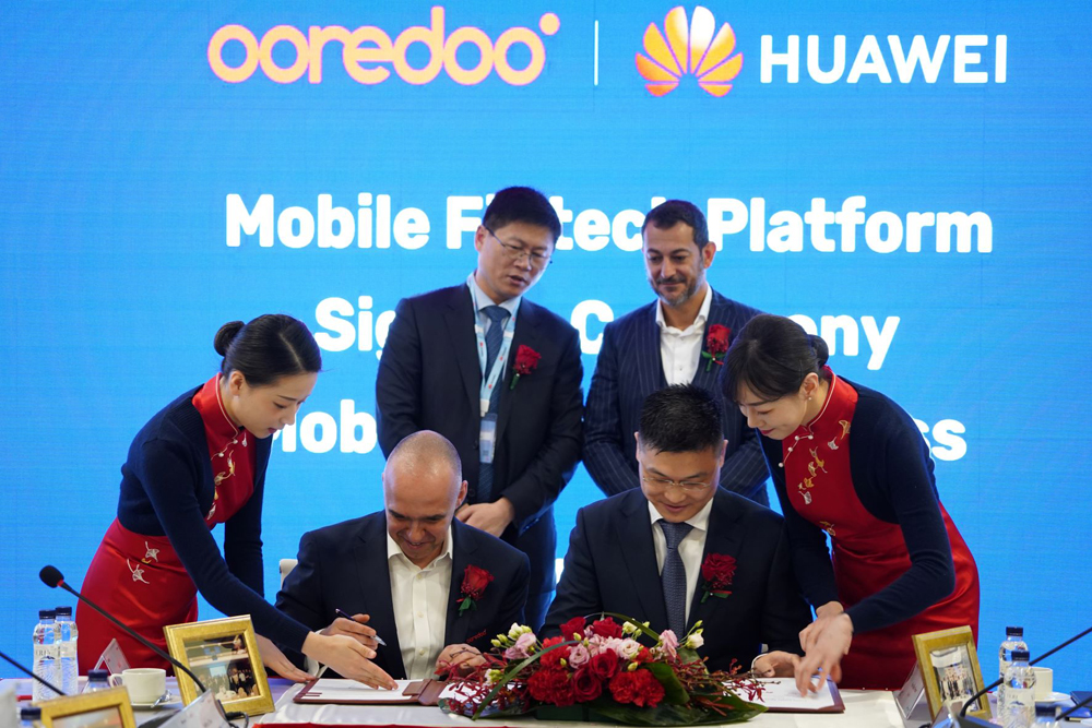 Ooredoo and Huawei officials sing the agreement.