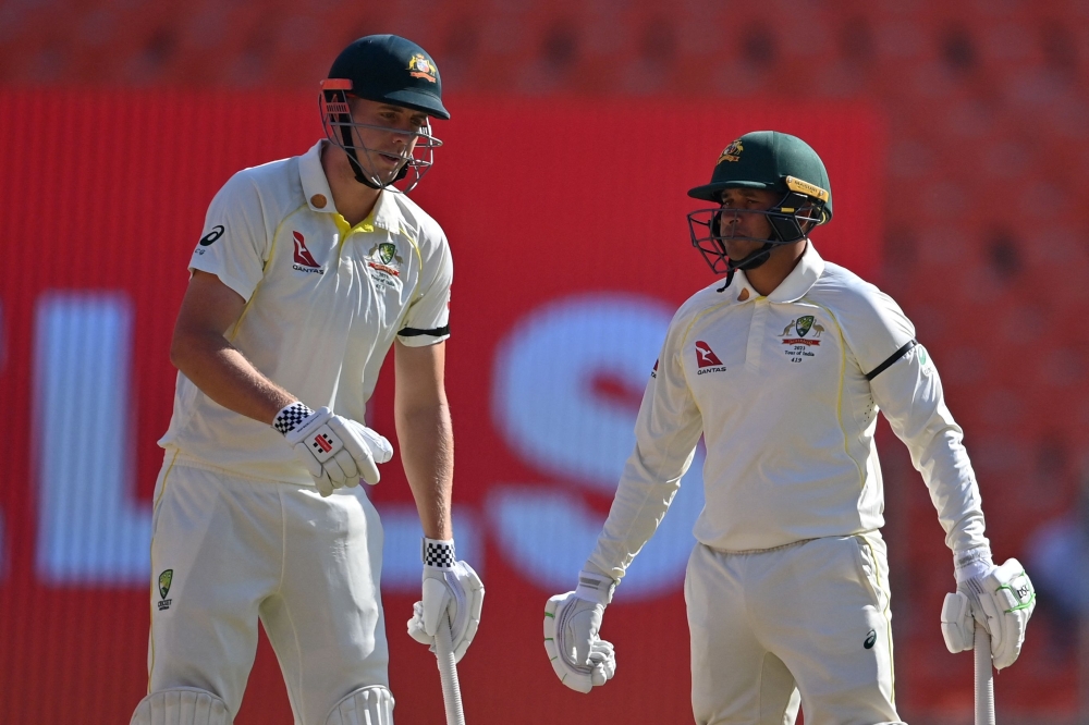 Australia's Usman Khawaja (R) and Cameron Green wear black armbands following the death of skipper Pat Cummins' mother as they wait for the start of the second day play of the fourth and final Test cricket match between India and Australia at the Narendra Modi Stadium in Ahmedabad on March 10, 2023. (Photo by Punit PARANJPE / AFP)