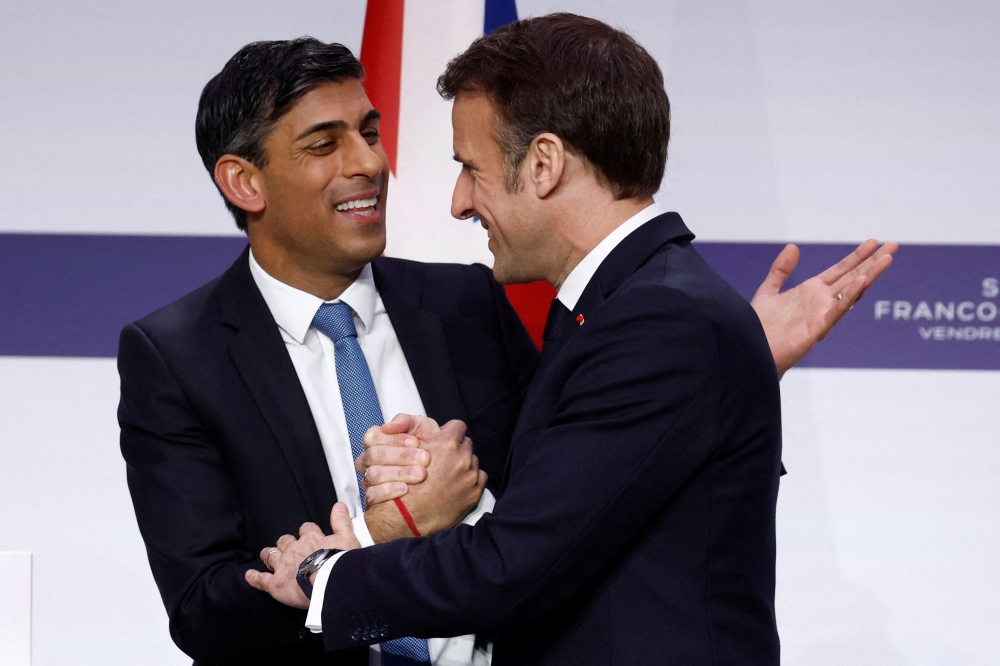 French President Emmanuel Macron shakes hands with British Prime Minister Rishi Sunak at the end of a press conference with British Prime Minister as part of the Franco-British Summit held at the Elysee Palace in Paris, on March 10, 2023. (Photo by GONZALO FUENTES / AFP)