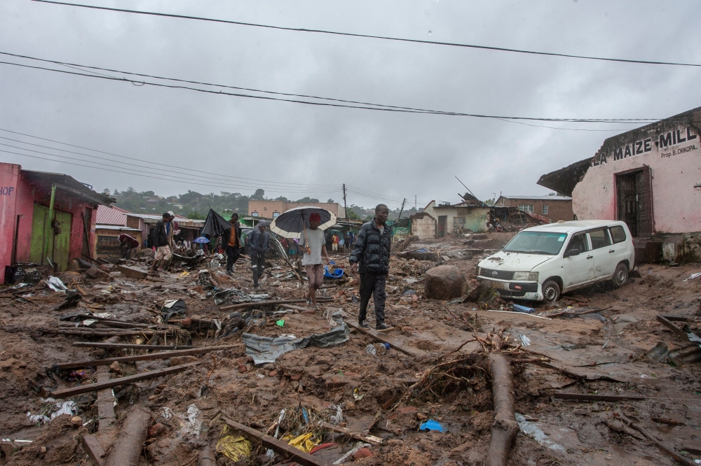 People wander in the water flooded affected Chimwankhunda location in Blantyre on March 14, 2023 following heavy rains caused by cyclone Freddy. (Photo by Amos Gumulira / AFP)