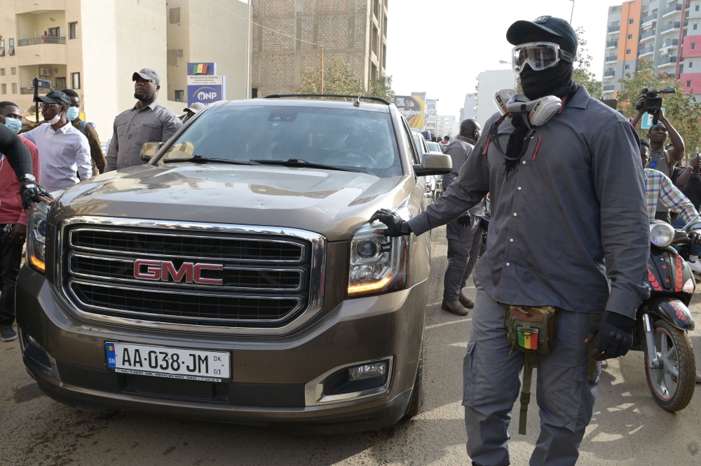 Members of the security team of Senegalese opposition leader Ousmane Sonko surrounds the vehicle he is travelling in to go to a court appearance in Dakar on March 16, 2023.  (Photo by SEYLLOU / AFP)