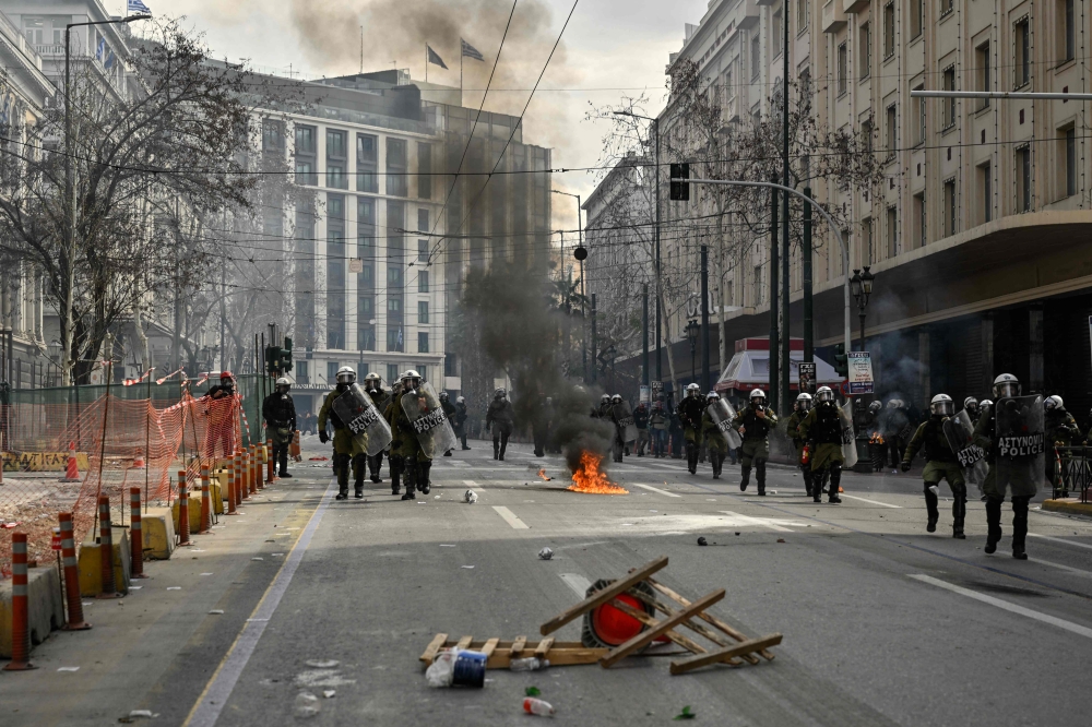 Police chases protesters in the center of the capital, as clashes broke out during a 24-hour strike in Athens on March 16, 2023. Photo by Louisa GOULIAMAKI / AFP