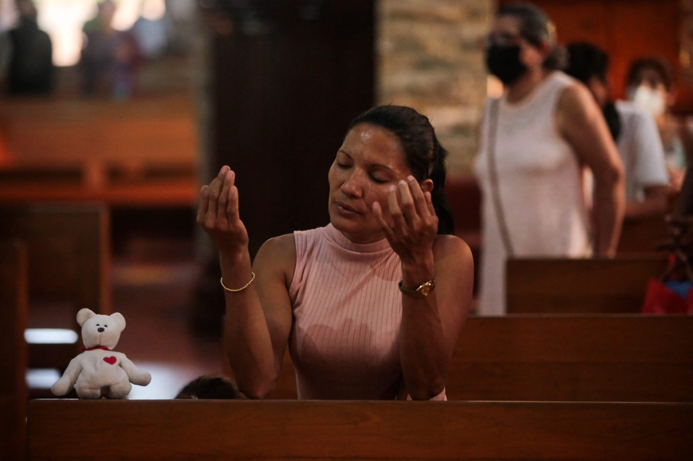 A woman prays before a Viacrucis at the Metropolitan Cathedral in Managua, on March 17, 2023. (Photo by OSWALDO RIVAS / AFP)