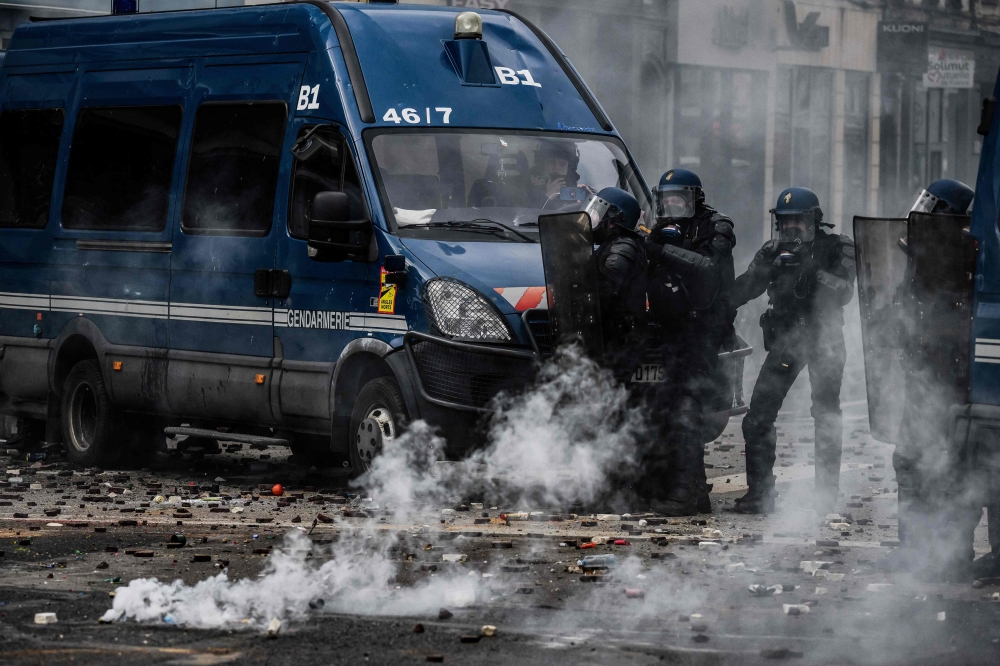  Police officer stand near tear gas during a demonstration, a week after the government pushed a pensions reform through parliament without a vote, using the article 49.3 of the constitution, in Lyon, central France, on March 23, 2023. Photo by JEFF PACHOUD / AFP