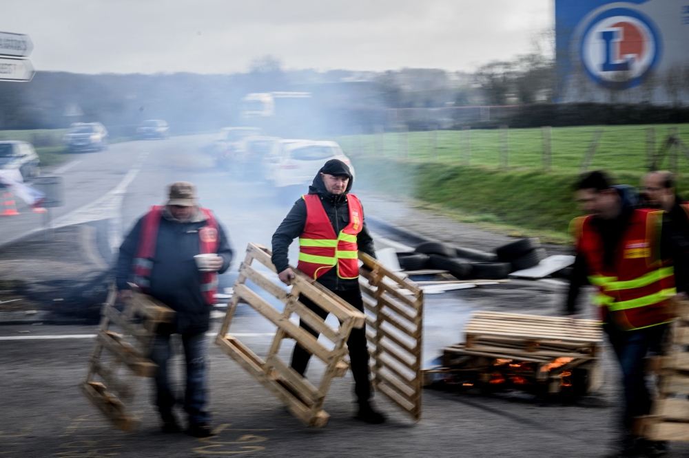 Unionists blockade the entrance to the E. Leclerc retail store dispatch center as protests continue across France after the French government pushed a pensions reform through parliament without a vote, using the article 49.3 of the constitution, in Saint-Etienne-de-Montluc, on March 24, 2023. (Photo by LOIC VENANCE / AFP)