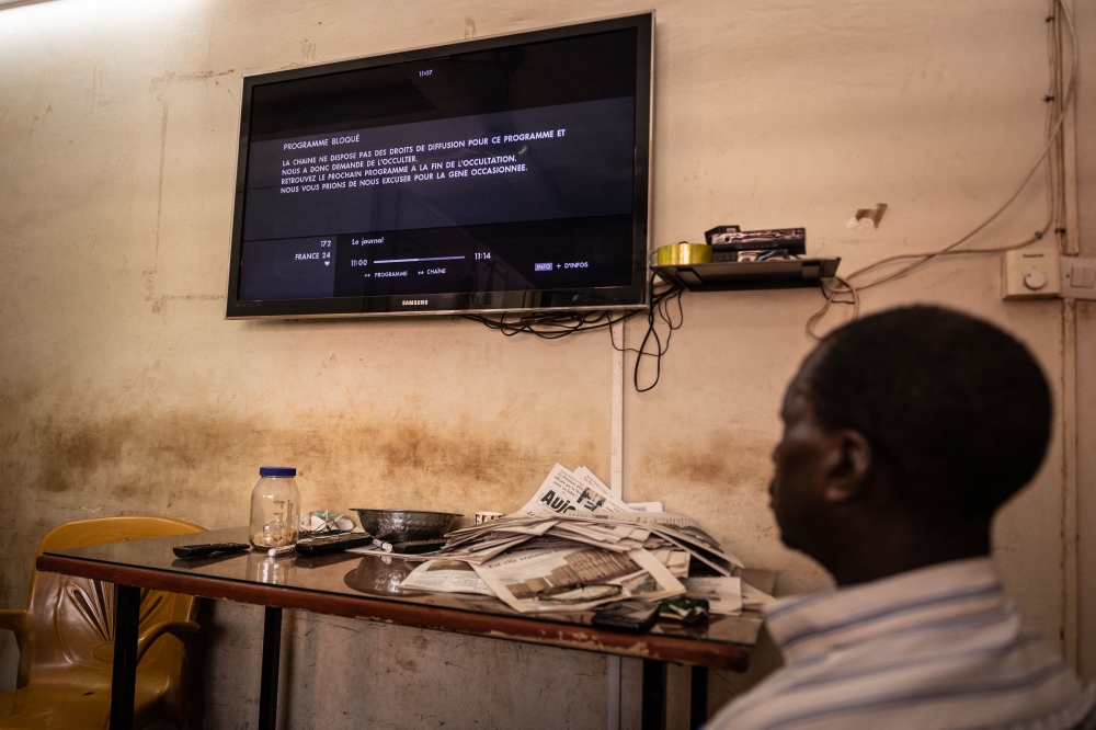 A man watches a television showing the cut signal of the France 24 channel, hours after the ruling junta in Burkina Faso decided to suspend the channel, in Ouagadougou, on March 27, 2023. 
(Photo by OLYMPIA DE MAISMONT / AFP)
 
