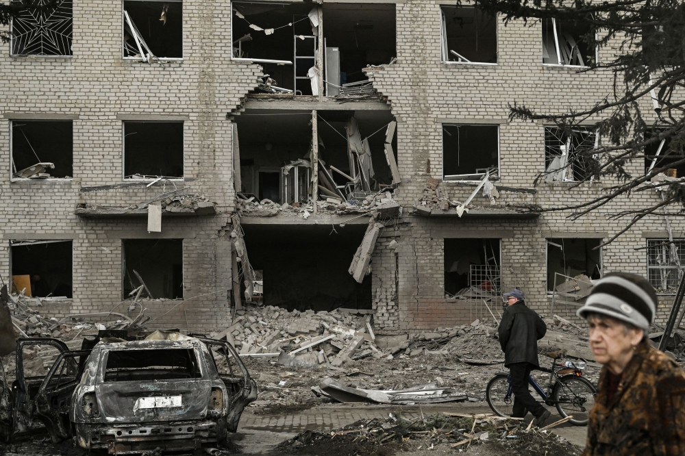 People walk in front of a destroyed building after a deadly strike in the city of Sloviansk, on March 27, 2023. Photo by Aris Messinis / AFP