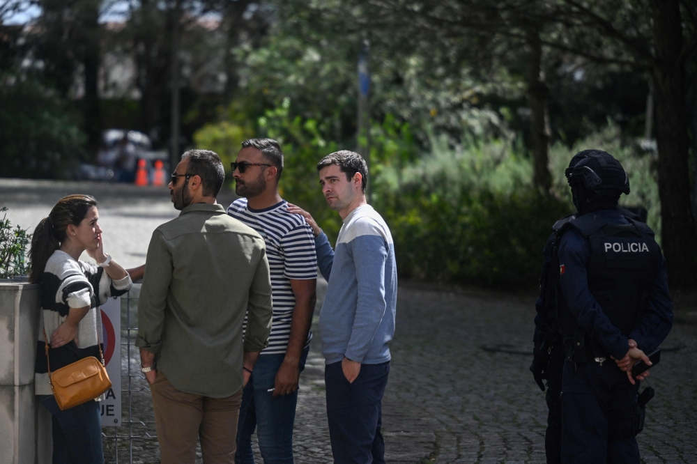 A Portuguese police officer stands guard as people gather in front of the Ismaili Islamic centre in Lisbon, after two people died following a knife attack that wounded several others, on March 28, 2023.  (Photo by PATRICIA DE MELO MOREIRA / AFP)