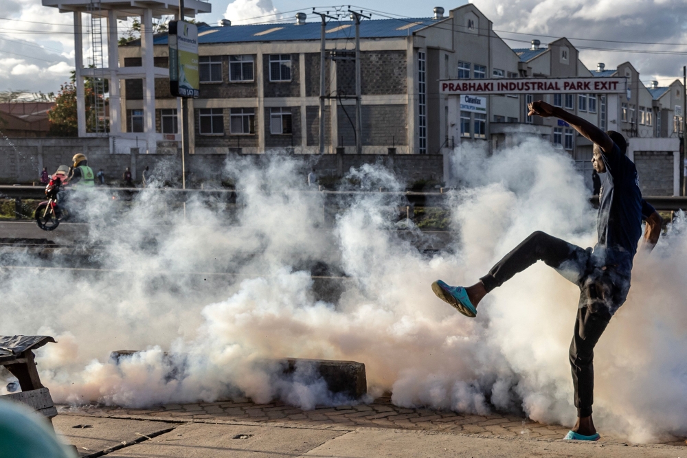 An opposition supporter kicks a teargas canister thrown by Kenya Police Officers during clashes at the informal settlement of Mathare in Nairobi, Kenya on March 27, 2023. (Photo by Luis Tato / AFP)