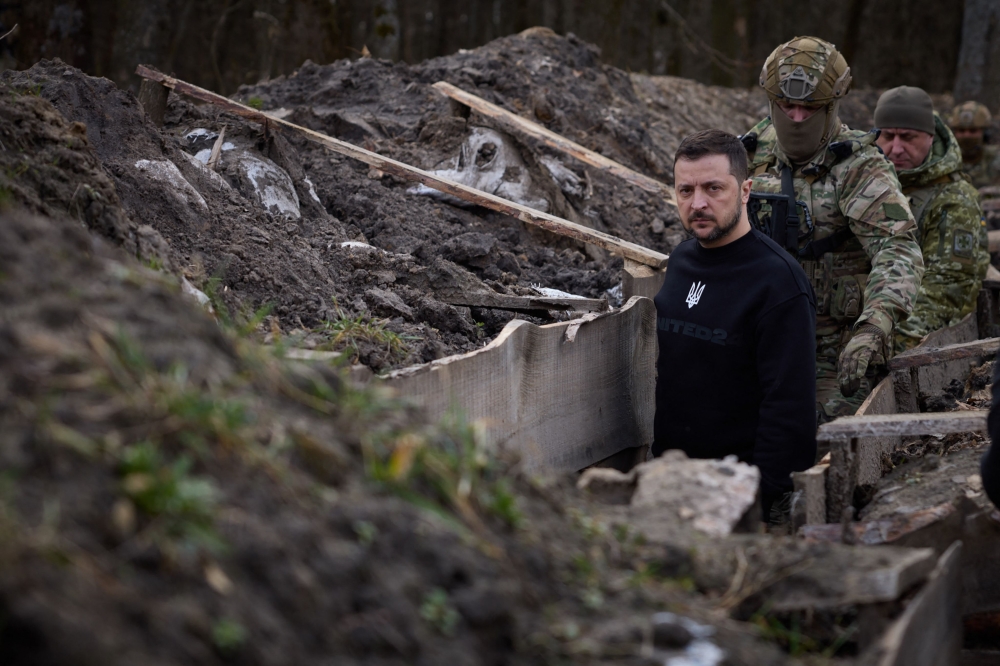 This handout photograph taken and released by Ukrainian Presidential Press Service on March 28, 2023 shows President Volodymyr Zelensky walking along tranches with border guard officers as he inspects the state border with Russian Federation in Sumy region. (Photo by Handout / Ukrainian Presidential Press Service / AFP)